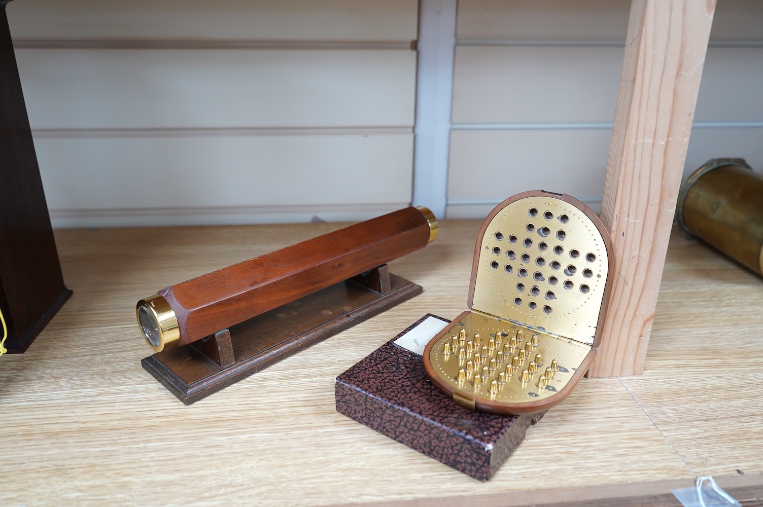 A reproduction 19th century style wooden bodied kaleidoscope on stand, 29.5cm, together with a wood cased brass solitaire set (one peg missing), 10.5cm diameter. Condition - fair.